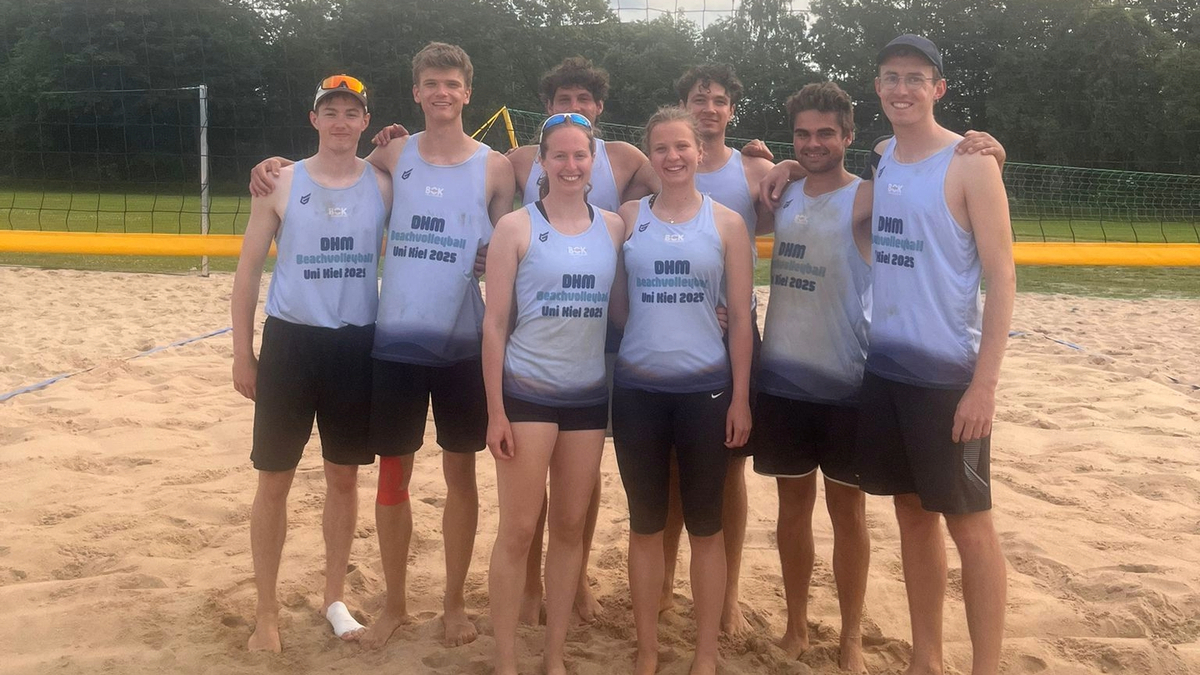 Eine Gruppe von Beachvolleyballspielern steht auf einem Sandfeld.